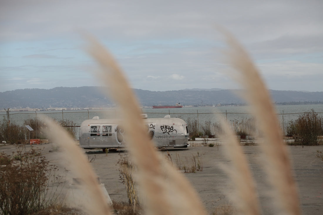 Two vintage trailers parked near a bay.
